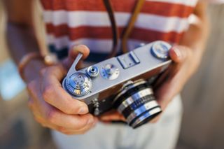 Close up analog camera in hand, sunny weather