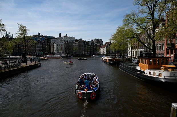 A boat moves along a canal in Amsterdam, on April 12, 2024. (Photo by JOHN THYS/AFP) (Photo by JOHN THYS/AFP via Getty Images)