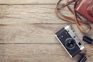 A movie camera and a roll of film on a wooden table